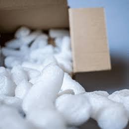 White loose fill spilling out of an open kraft carton.