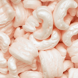 A close-up of pale pink S-shaped loose fill packing peanuts filling the frame.