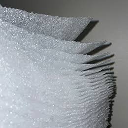 A stack of pre-cut white polyethylene foam sheets, layered edges fanning out.