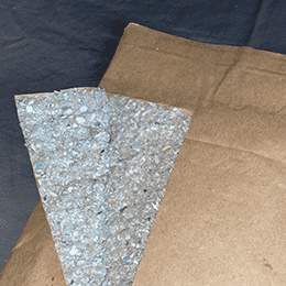 Kraft mailer stock folded back to show the grey macerated-paper padding inside it.